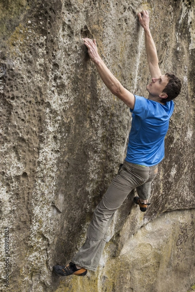 Fototapeta Athlete climbs on rock with rope.
