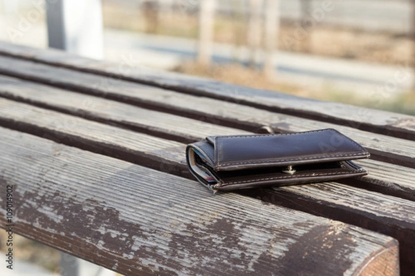 Fototapeta Lost brown leather wallet laying on bench