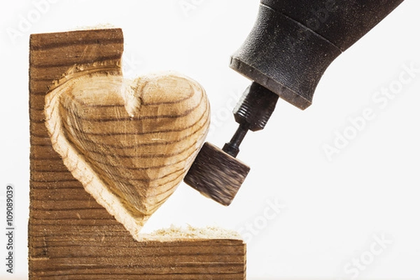 Obraz Sanding wood in heart shape with a rotary tool, on white, horizontal
