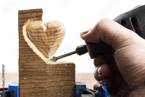 Obraz Carving wood in heart shape with rotary tool, on white background