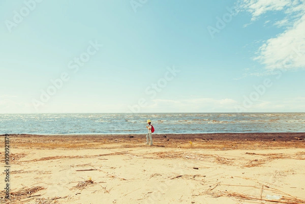 Obraz a man with a backpack is walking along the beach