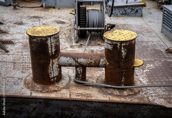 Obraz Rusty Bollards and Winch on a Ship's Deck - Nautical, Maritime, Industrial, Metal, Rust, Corrosion, Texture, Pattern, Detail, Close-up, Macro, Shipyard, Harbor, Port, Dock, Pier, Water, Ocean, Sea, Bo