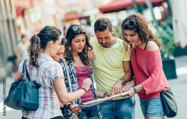 Obraz group of tourists using map in the city
