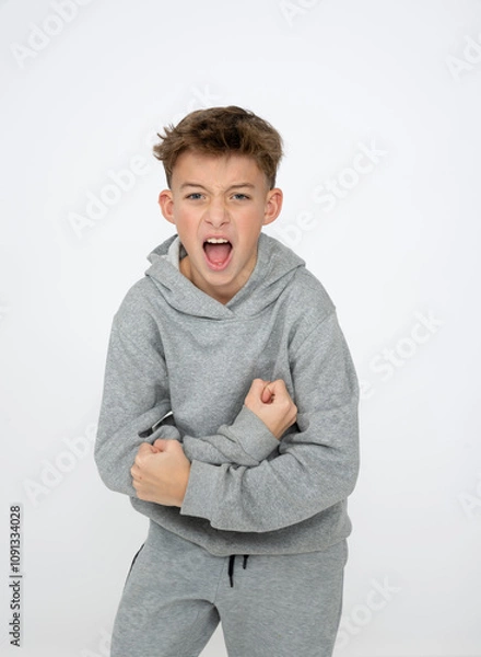 Obraz cool young 12 year old boy with grey hoody sweater posing in front of white background, having fun