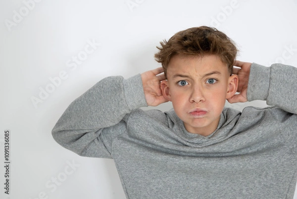 Obraz cool young 12 year old boy with grey hoody sweater posing in front of white background, having fun