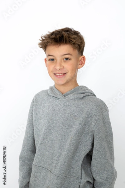 Obraz cool young 12 year old boy with grey hoody sweater posing in front of white background, having fun
