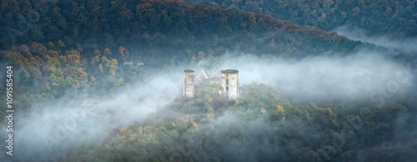 Obraz panorama of atmospheric morning with fog between hills and ruins of medieval castle in centre with copy space