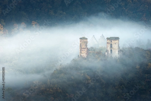 Obraz landscape in morning twilight with waves of fog around ruins of castle and church