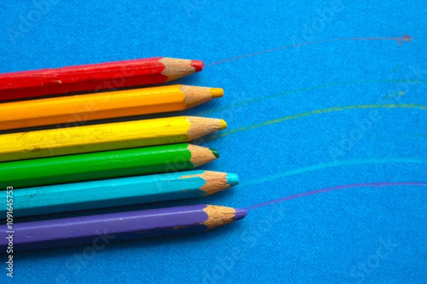 Fototapeta colored wooden pencils in a row, on blue background. top view