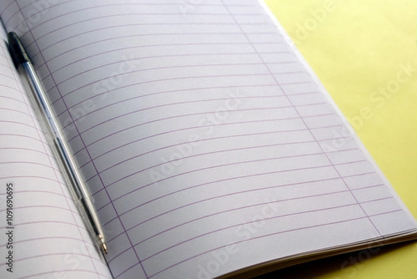 Fototapeta  open notebook, with a black pen on , on yellow background.selective focus
