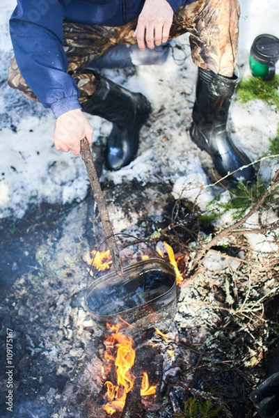 Obraz The man boils the pot on the fire