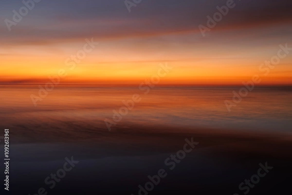 Obraz Long exposure abstract fine art photography of a red and orange sunset over the ocean. 