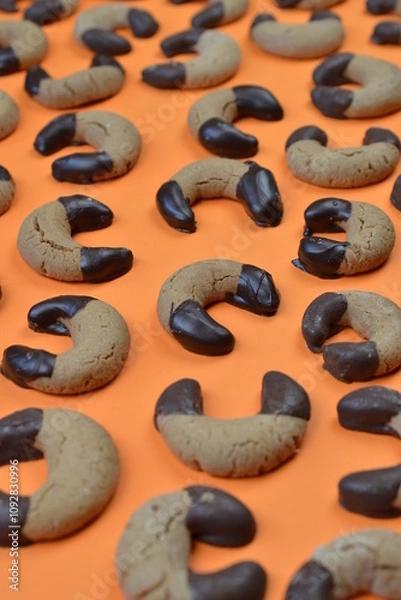 Fototapeta pattern out of home made nougat crescents cookies with chocolate at the edges on orange background 