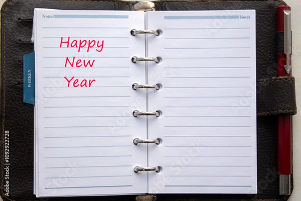 Fototapeta close up  of an open daily brown calendar with silver rings isolated on white background. Happy New Year written on with red letters