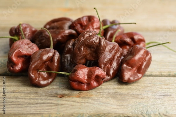 Fototapeta Brown Habanero peppers on wooden background, Habanero Chocolate, selective focus, bokeh, red habanero background, pepper background, space for text, copy space.