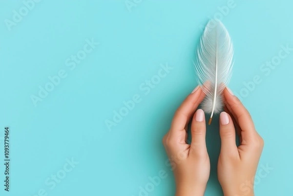 Obraz Female hands gently holding a delicate white feather on a vibrant turquoise background suggesting peace and tranquility in minimalism