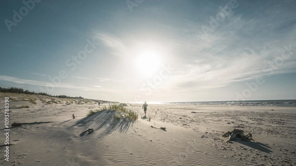 Fototapeta Two individuals strolling along a sandy beach close to the ocean waves