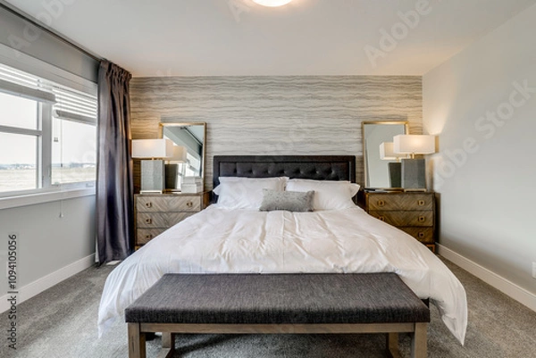 Fototapeta A large bed with a gray and white bedspread and pillows