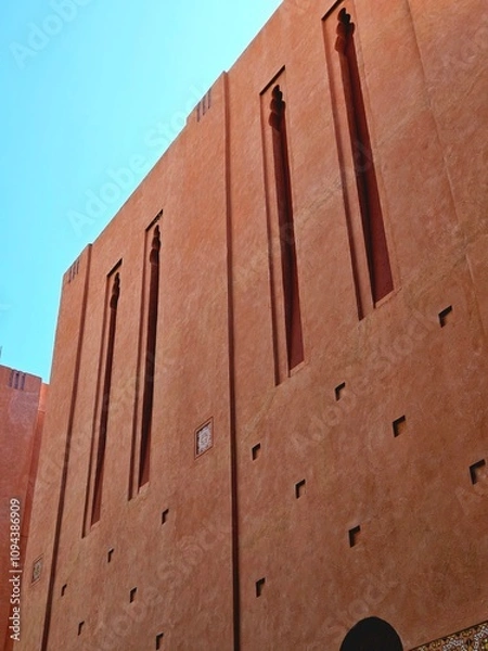 Fototapeta Beautiful Moroccan-style hotel building with blue sky and sunlight. Abstract portrait wallpaper.