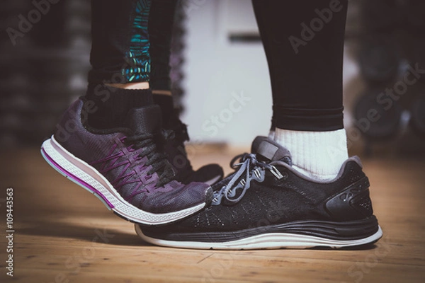 Fototapeta Closeup of sneakers. Girl standing on toes to kiss boyfriend. Couple workout concept. Love sports concept.