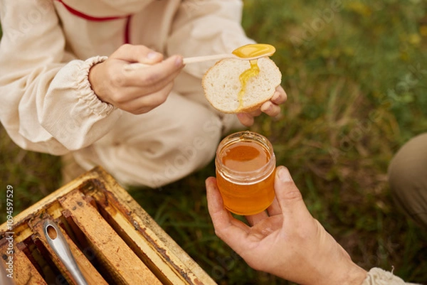 Obraz A child's hands spreading honey on a slice of bread.