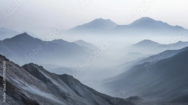 Fototapeta A mountain range shrouded in smog, where the peaks are barely visible, and the surrounding valleys are filled with gray haze. 
