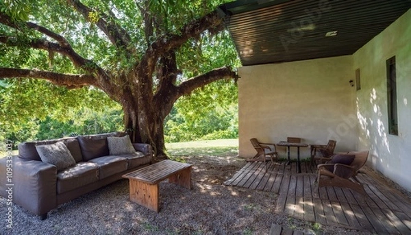 Fototapeta 큰 나무 아래 대화를 할 수 있는 소파와 테이블이 놓여있다