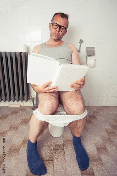 Obraz Man in restroom reading a book
