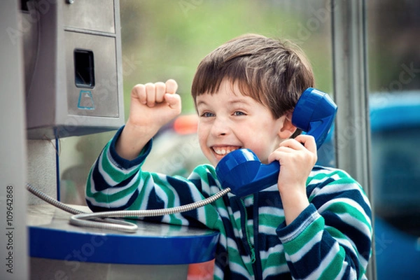 Fototapeta Cute little boy talking on the public phone