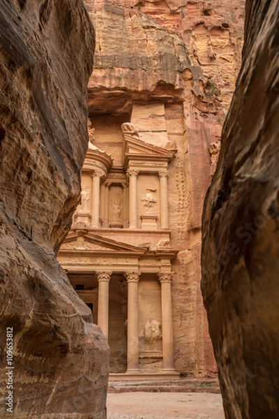 Fototapeta Hiking through the canyon in the ancient city of Petra (Jordan) - opening view of the famous Al-Khazneh (aka Treasury)