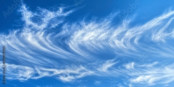 Fototapeta A Captivating Celestial Dance: Delicate Cloud Formations Against a Vibrant Blue Sky