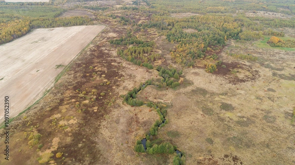 Fototapeta Dry, brown field with a river running through it