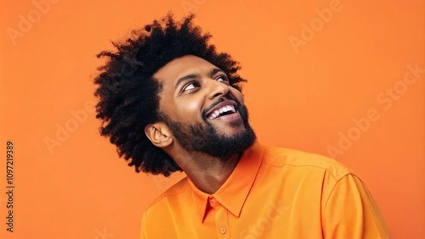 Fototapeta A vibrant portrait of an artist wearing a bright orange shirt with an equally vivid orange background. Their animated expression conveys creativity and enthusiasm while the