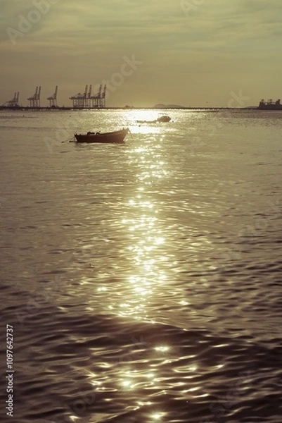 Fototapeta The ocean's mirror reflects the golden hues of the setting sun