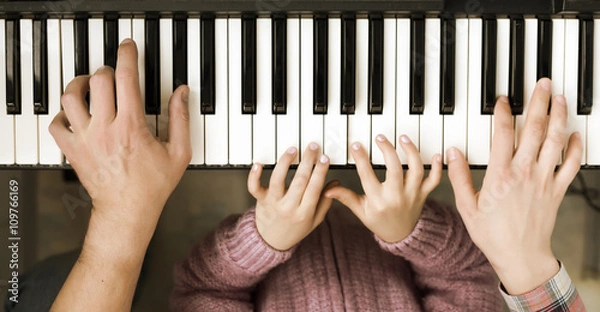 Fototapeta Piano Keyboard top View and Hands of Child Mother and Father