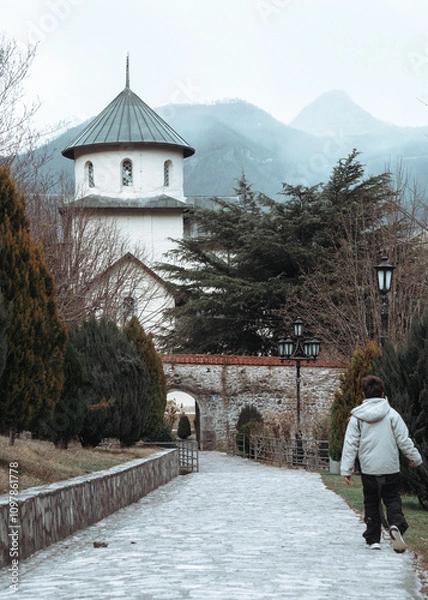 Obraz A little boy is walking down the path toward the monastery. Autumn day
