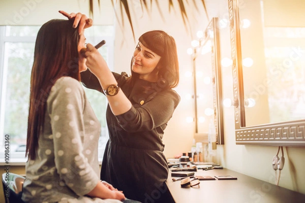 Fototapeta Professional expert,makeup artist prepares very beautiful,young,well-known,glamorous,stunning model for filming shooting for cover of fashion magazine VOGUE,does make-up,makes up lips,art,eyes,white.