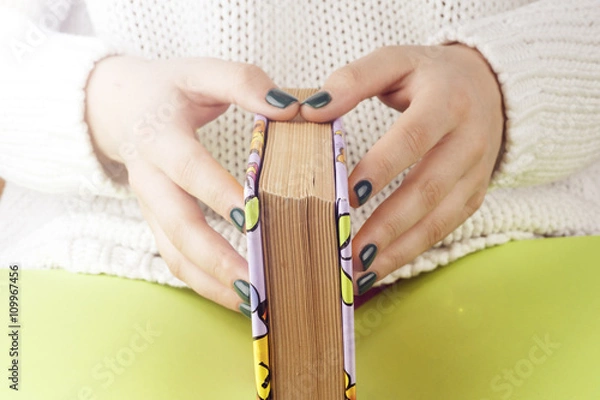 Fototapeta Young girle reading an  open book . old book. Books and reading are essential for self improvement, gaining knowledge and success in our careers, business and personal lives.