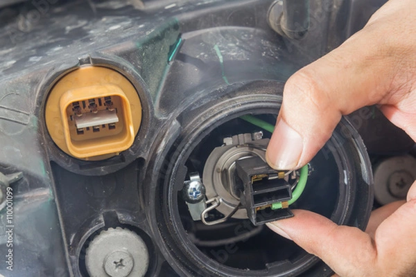 Fototapeta Mechanic changing car headlight in a workshop