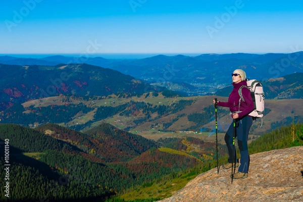 Fototapeta Hiker Staying on High Rock and Mountain View with Autumnal Forest
