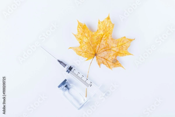 Fototapeta Autumn maple leaf and syringe with vaccine on white background. Vaccination against colds..
