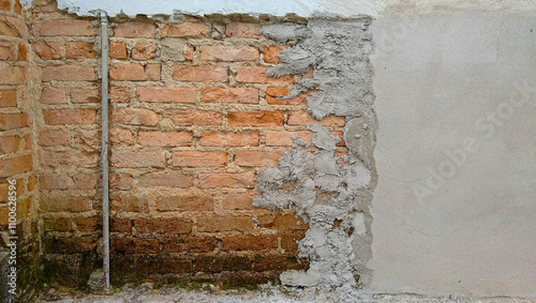Fototapeta section of old masonry wall undergoing renovation with exposed solid brick section with vertical hydraulic installation pipe and a section with newly installed cement plaster