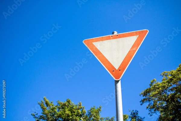 Fototapeta german give way sign with blue sky in the background and trees on the side