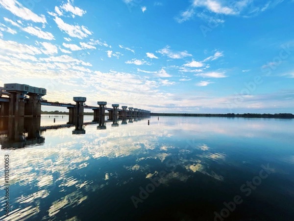 Fototapeta 夕刻時の川面に反射する水門と空模様