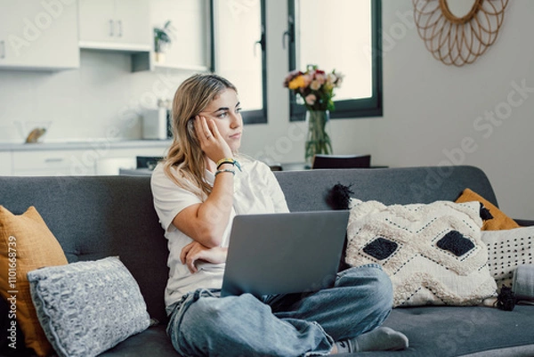 Fototapeta One caucasian unhappy girl looking outside sitting on sofa using laptop computer thinking on problems. Female worried woman studying and working.