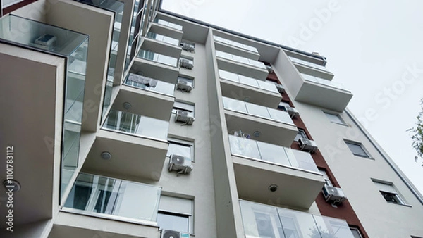 Fototapeta Photo of Low-Angle View of a Modern Apartment Building with Glass Balconies and Air Conditioners