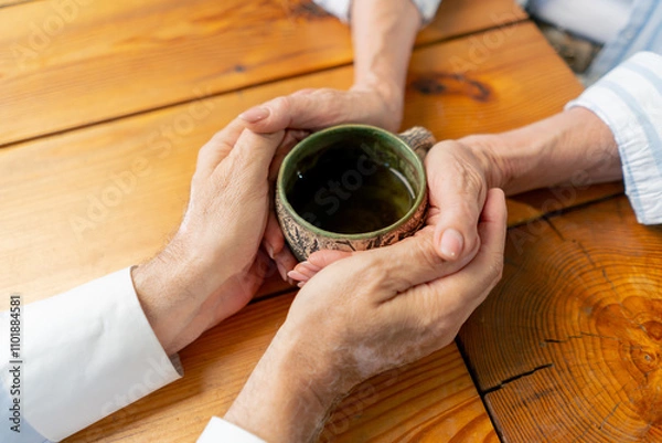 Fototapeta close up hands elderly people sitting at the table woman with a cup of tea happy old age elderly couple pleasant memories leisure time in old age warm feelings support in old age difficult times