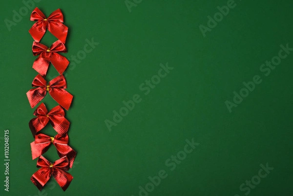 Fototapeta Red bright festive bows on a green background. Christmas decorations. Copy space, flat lay