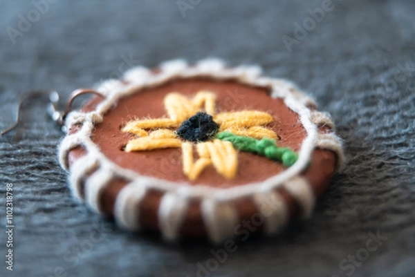 Fototapeta A handmade terracotta ornament featuring a sunflower design, intricately woven with yarn, creating a unique blend of natural materials and textile art