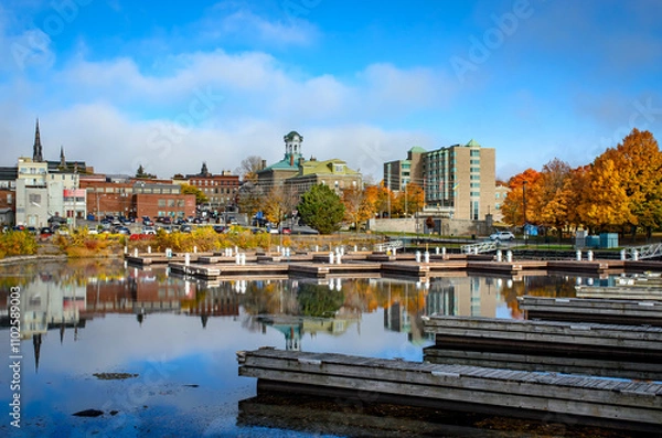Obraz View from the empty marina harbour showing Brockville's city hall and downtown buildings with trees in autumn color,